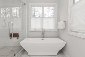 uma casa de banho branca com uma grande banheira e janelas em Villa Kimaal - Luxury with pool em Sag Harbor