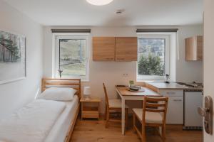 a small room with a bed and a table and a kitchen at Kalkalpen Apartments in Spital am Pyhrn