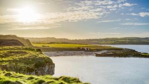 a body of water with the sun in the background at Moryn in Moelfre