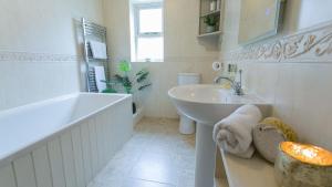 a white bathroom with a sink and a tub and a sink at Moryn in Moelfre