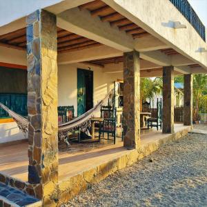 a porch of a house with a hammock on it at CHEVERE BEACH CABAÑAS SAS in Puebloviejo
