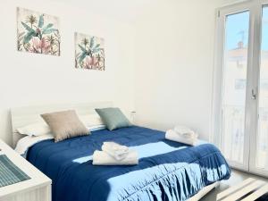 a bedroom with a bed with blue sheets and a window at DOLCE VITA Sperlonga - UN LETTO IDEALE in Sperlonga