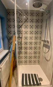 a shower with a black and white patterned wall at Little Lopsi in Detmold
