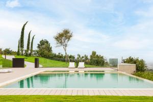 a swimming pool in the middle of a lawn with two lounge chairs at Villa Santa Maria Maddalena by Palazzo di Varignana in Casalecchio deʼ Conti