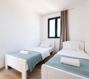 2 Betten in einem Zimmer mit weißen Wänden in der Unterkunft Villa Azul in Šimanovci