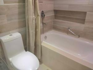 a bathroom with a white toilet and a bath tub at Bel's 2 Bedroom Condo in Santorini Hotel Sta. Lucia Mall Cainta Rizal in Manila