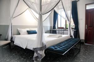 a bedroom with a canopy bed with a bench at Explorers Hub in Kampala