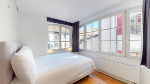 1 dormitorio con cama blanca y ventanas en Charming apartments in the center of Lutry en Lutry