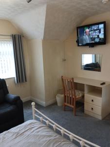 um quarto com uma televisão na parede e uma cama em Seaforth Guest House - Pleasure Beach em Blackpool