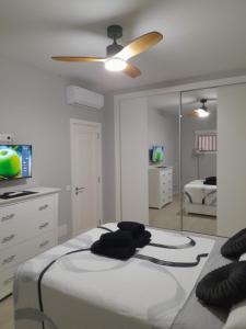 1 dormitorio con 1 cama con ventilador de techo y espejo en Casa Lola, en Maspalomas