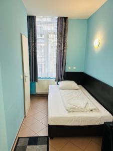 - une chambre avec un lit dans une pièce bleue dans l'établissement Angel Hotel, à Francfort-sur-le-Main