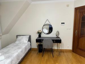 a bedroom with a bed and a desk with a mirror at Villa Sophie in Żabno