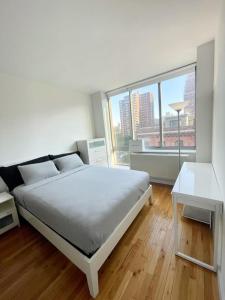 a white bedroom with a bed and a large window at 2 bedrooms Chelsea apartment - Manhattan in New York
