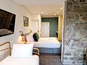 a bedroom with two beds and a stone wall at Wheal Tor Hotel & Glamping in Liskeard