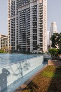 a swimming pool in front of a tall building at Burj Khalifa View & Creek lagoon in Dubai