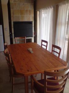 a wooden dining room table with chairs and a television at Calypso Beach Holiday House in Langebaan +14 photos
