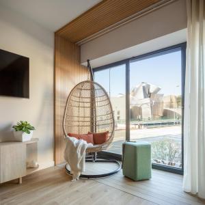 Apartamentos Líbere Bilbao Museo في بلباو: كرسي معلق في غرفة مع نافذة كبيرة