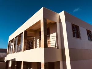 a white building with a blue sky in the background at Calypso Beach Holiday House in Langebaan