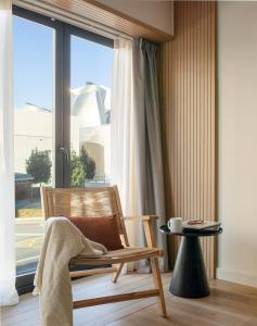 Apartamentos Líbere Bilbao Museo في بلباو: كرسي أمام نافذة مع طاولة