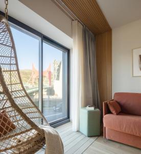 Apartamentos Líbere Bilbao Museo في بلباو: غرفة بها كرسي يتأرجح ونافذة كبيرة