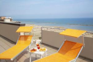 un balcone con 2 sedie, un tavolo e una spiaggia di Activ Hotel Salsedine a Rimini