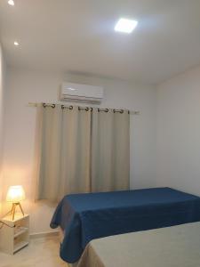 um quarto com uma cama com um cobertor azul e uma janela em Beach House Praia de Carapibus em Jacumã