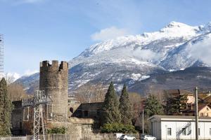 um velho castelo com uma montanha coberta de neve no fundo em Alpen Pila Residence Loft 1 em Aosta