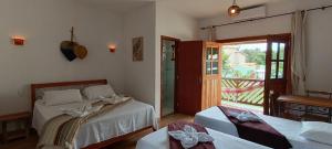 a bedroom with two beds and a door to a balcony at Pousada Real Cipo in Serra do Cipo