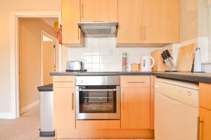 a kitchen with wooden cabinets and a stove top oven at Whippingham, Creek Gardens in Wootton Bridge