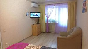 a bedroom with a television and a chair and a window at Apartment - Generala Petrova Street in Odesa