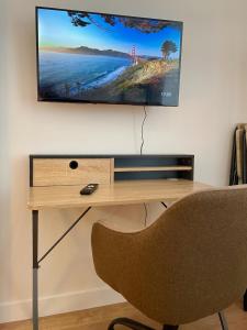 a desk with a television on a wall with a chair at Cocon zen du clocher - SOnights in Château-du-Loir +7 photos