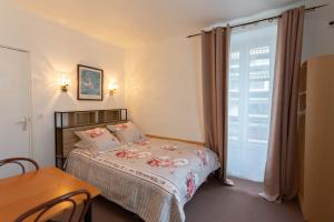 a bedroom with a bed and a table and a window at Ideal Hotel in Paris