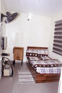 een kamer met 2 bedden en een stoel. bij Smilley's Place Szilvie in Lagos