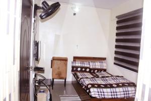 a room with two beds and a chair in it at Smilley's Place Szilvie in Lagos