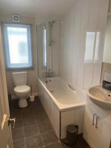 a bathroom with a tub and a toilet and a sink at 2 Bed Lodge Style Caravan with Hot Tub & Private Garden in Patrington