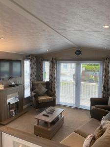 a living room with a couch and a tv at 2 Bed Lodge Style Caravan with Hot Tub & Private Garden in Patrington