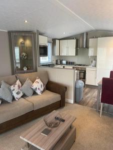 a living room with a couch and a kitchen at 2 Bed Lodge Style Caravan with Hot Tub & Private Garden in Patrington