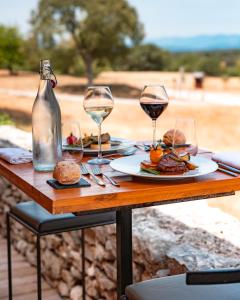 - une table avec des assiettes de nourriture et des verres à vin dans l'établissement Mas De Baumes, à Ferrières-les-Verreries