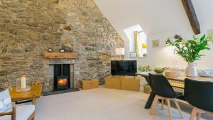 a living room with a stone wall with a fireplace at Custom Mews in Beaumaris
