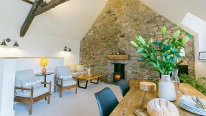 a living room with a table and a stone fireplace at Custom Mews in Beaumaris