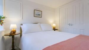a bedroom with a white bed and two lamps at Custom Mews in Beaumaris