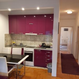 a kitchen with purple cabinets and a dining table at Lili in Arandjelovac