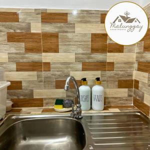 um lavatório de cozinha com duas garrafas brancas na parede em Malunggay Apartments em Mariveles