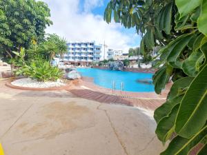 uma piscina com um hotel ao fundo em Golf del sur deluxe em San Miguel de Abona