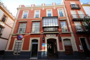 a red building with windows and a blue sign in front at Hotel Maestranza in Seville