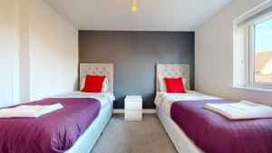 2 camas en una habitación con almohadas rojas en Tms Lovely 5-Bed House in Stanford-le-Hope, en Stanford-le-Hope