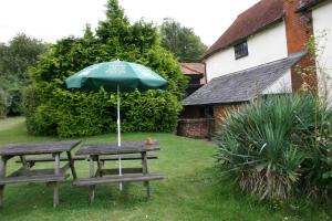 a picnic table with an umbrella and two benches at Farmhouse Inn in Thaxted