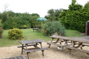 two picnic tables and an umbrella in a garden at Farmhouse Inn in Thaxted