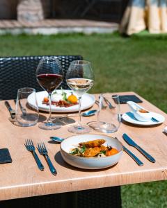 une table avec une assiette de nourriture et des verres de vin dans l'établissement Mas De Baumes, à Ferrières-les-Verreries