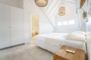 a white bedroom with a bed and a wooden table at Luxe pleine vue mer et plage in Saint-François